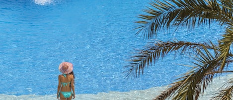 Een binnenzwembad, een buitenzwembad en parasols bij het zwembad