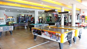 Una sala de billar con múltiples mesas, juegos de arcade y un suelo brillante de baldosas.