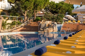 Area piscina con vista aperta sull'acqua, scalini di accesso e poltroncine da relax gialle.