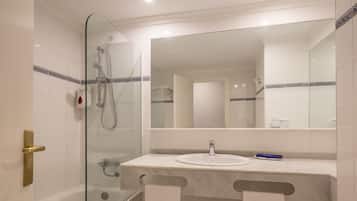 Een moderne badkamer met een douchecabine van glas, een wit wastafeltje en een grote spiegel.