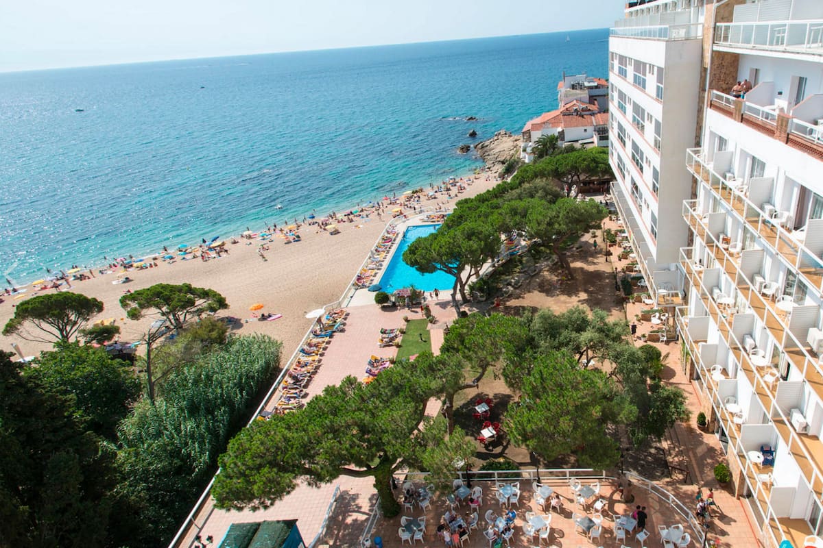 A hotel with a pool area, beach, and ocean view.