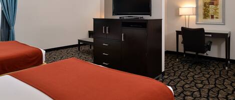 A hotel room with two beds, a TV on a cabinet, a desk with a chair, and a patterned carpet.
