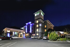Un hotel Holiday Inn Express & Suites con un estacionamiento y varios coches aparcados frente a él.