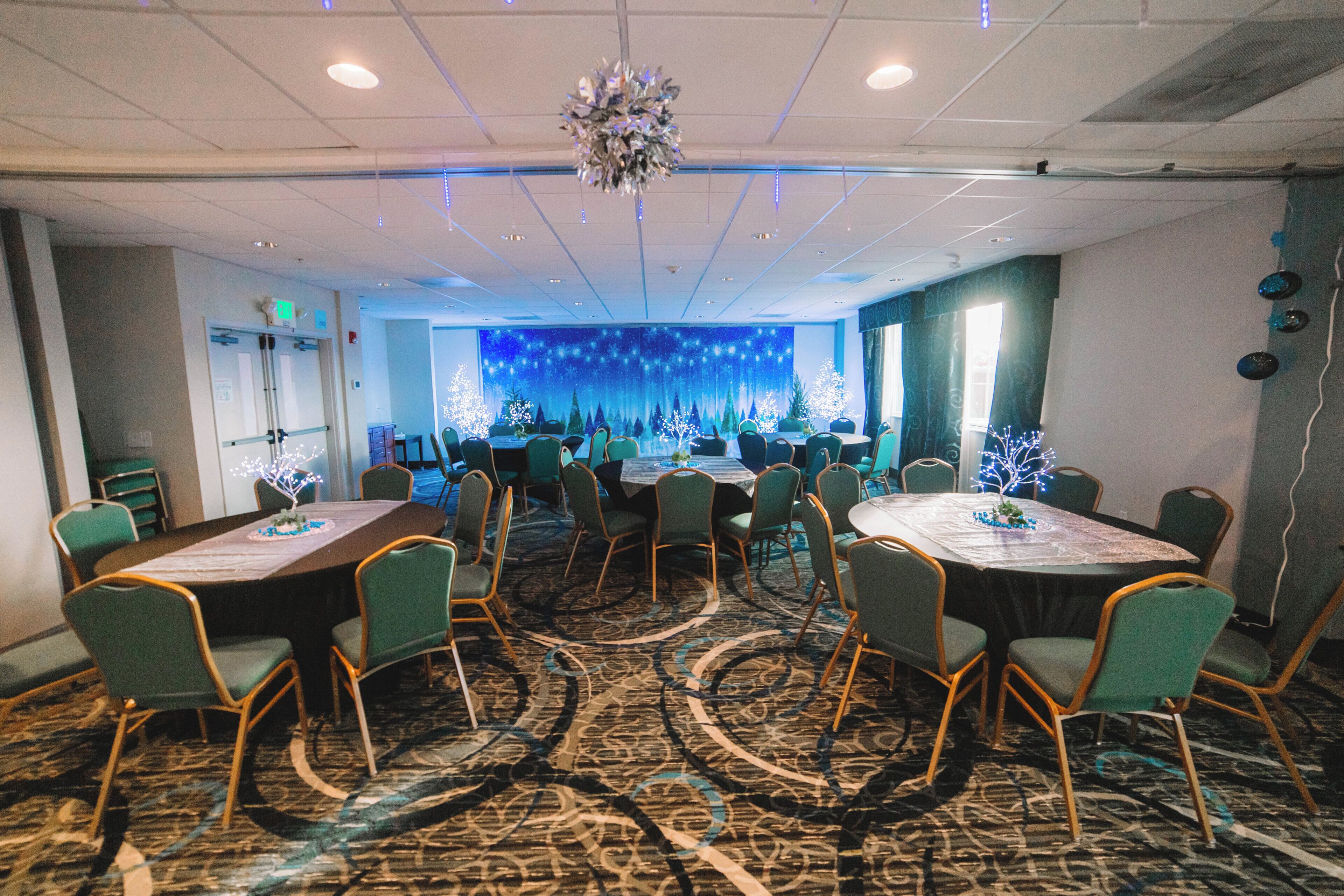 A conference room with round tables and chairs, a patterned carpet, and a decorative backdrop.