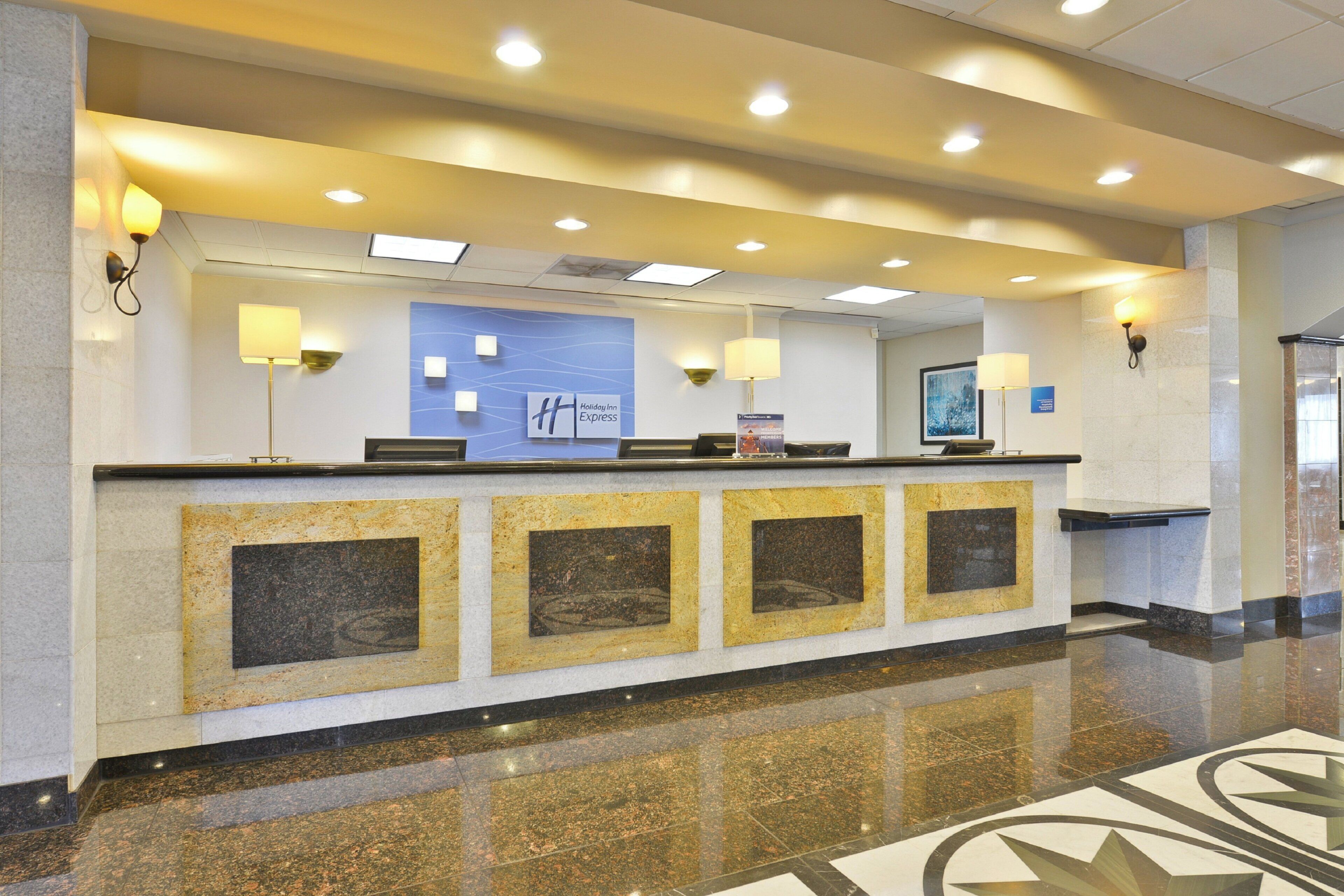 A hotel reception desk with a blue sign, multiple light fixtures, and a polished floor.
