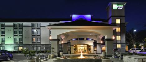 L’entrée d’un hôtel avec une fontaine, une enseigne indiquant « Holiday Inn Express & Suites » et un parking.