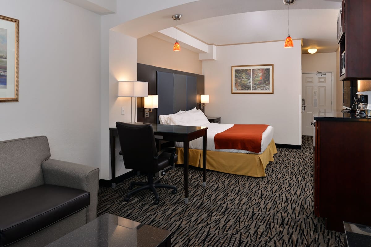 Une chambre d’hôtel avec un lit, un bureau, une chaise et un canapé.