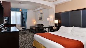 A hotel room with a large bed, a desk, a chair, a television, and a window with curtains. - Holiday Inn Express & Suites Tacoma South - Lakewood by IHG (Lakewood)
