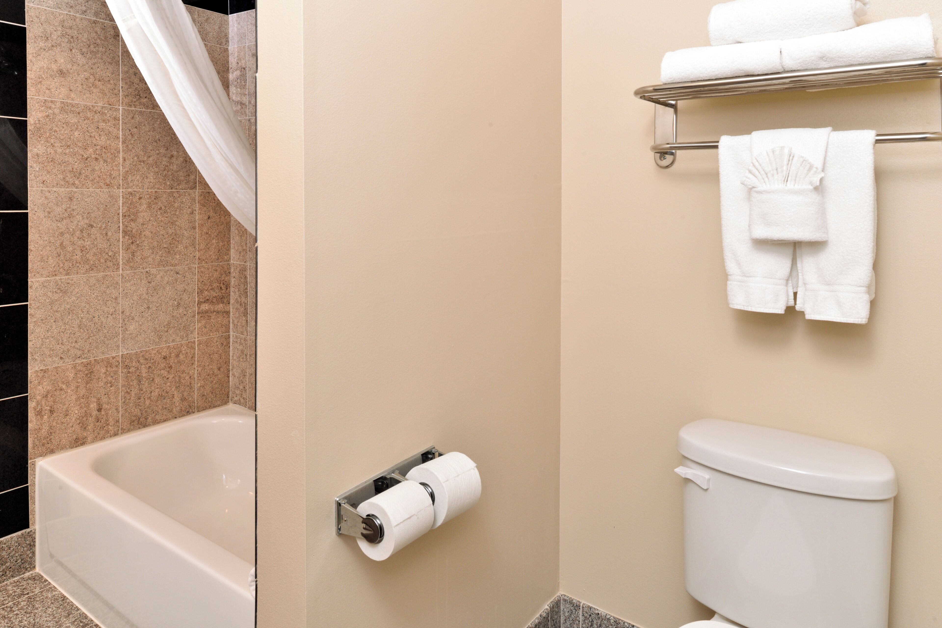 A bathroom with a bathtub, toilet, and a towel rack with towels.