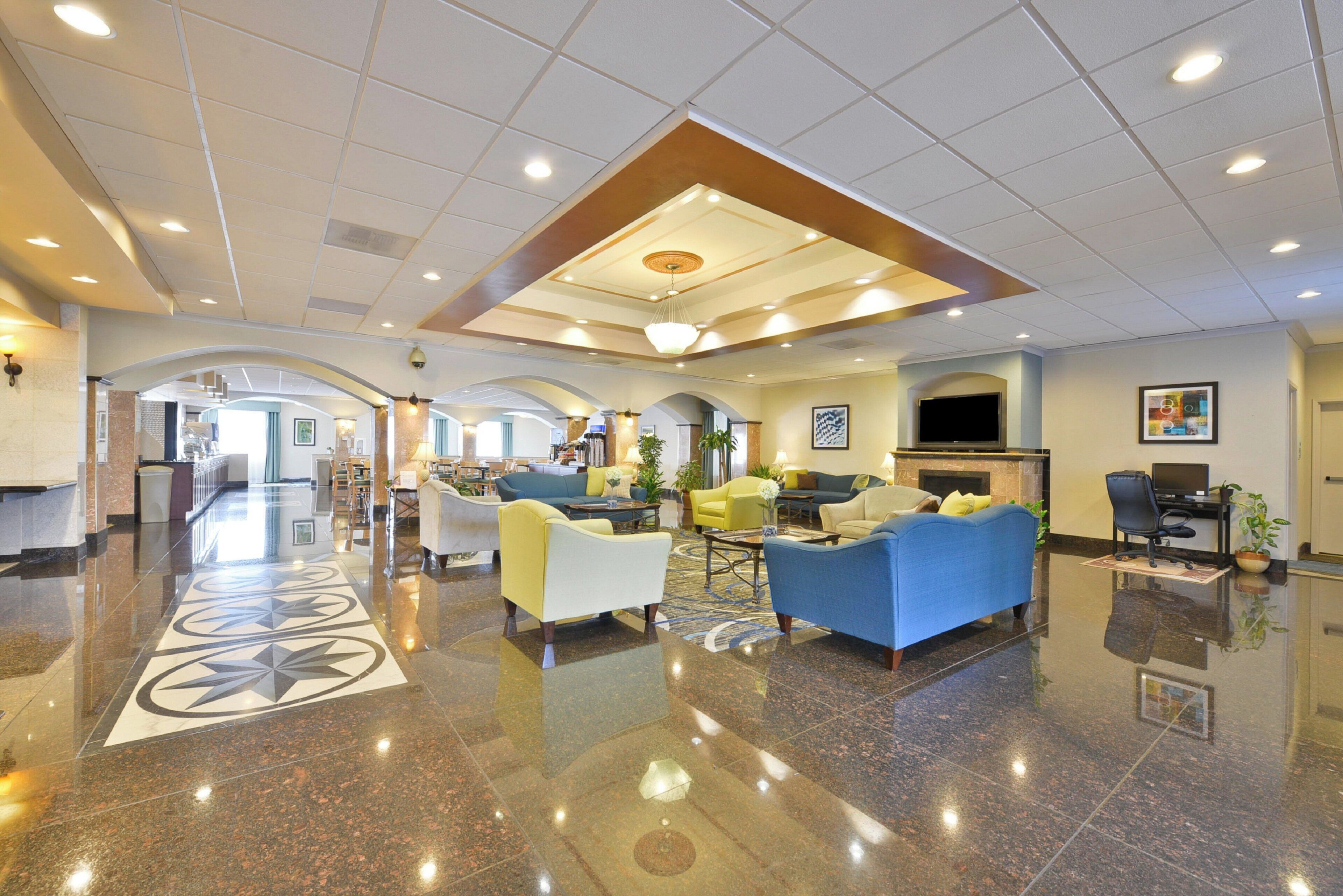 A spacious lobby with a polished marble floor, multiple seating areas, and a high ceiling with recessed lighting.