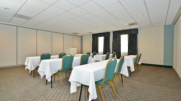 Ett konferensrum med bord och stolar, ett mönstrat golv och ett tak med infälld belysning.