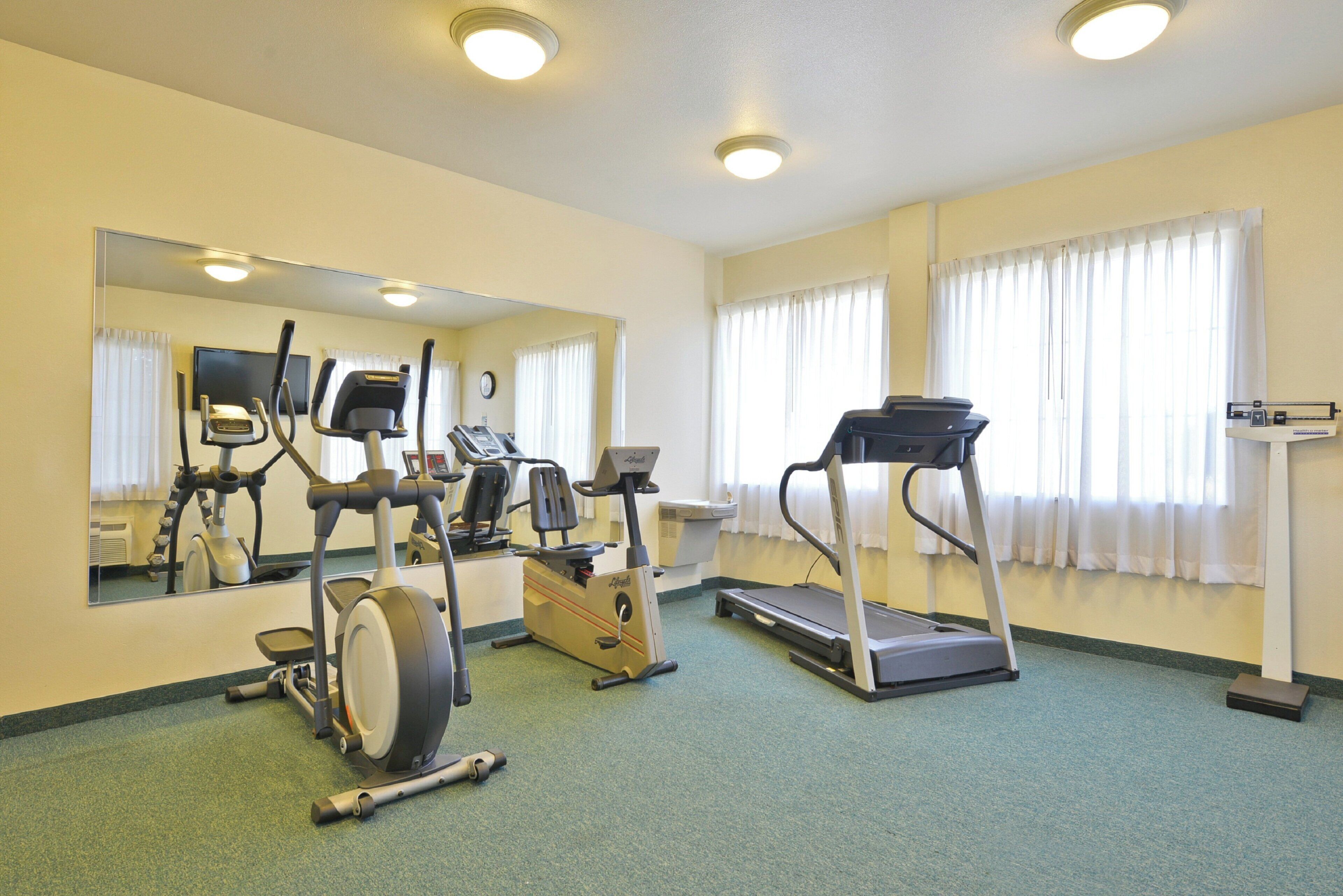 A fitness room with exercise equipment including treadmills, an elliptical, and a stationary bike.