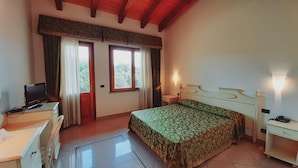 Une chambre à coucher avec un lit, un bureau, une chaise, un téléviseur et une fenêtre avec des rideaux.