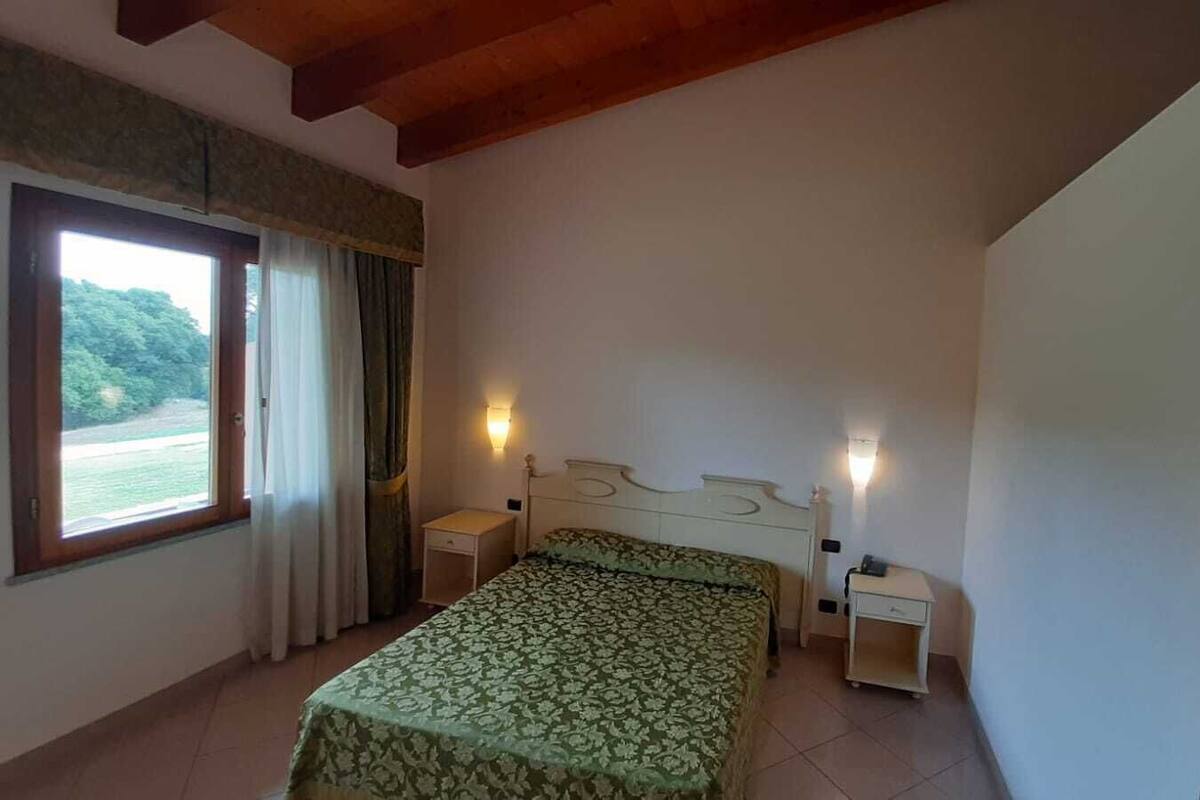 A bedroom with a bed, bedside tables, and a window with curtains.