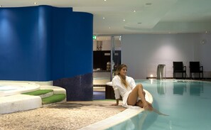Un espace piscine avec un mur bleu, un coin salon et un sol carrelé.