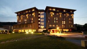 Ein mehrstöckiges Hotel mit Innenhof, großen Fenstern und Außenbereichen mit Sitzgelegenheiten.