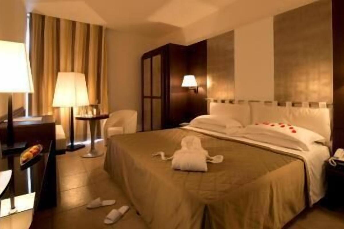 Una habitación de hotel con cama, lámparas de noche, escritorio y una silla.