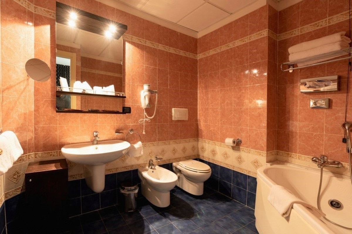 Een badkamer met een wastafel, toilet, bad en bidet.