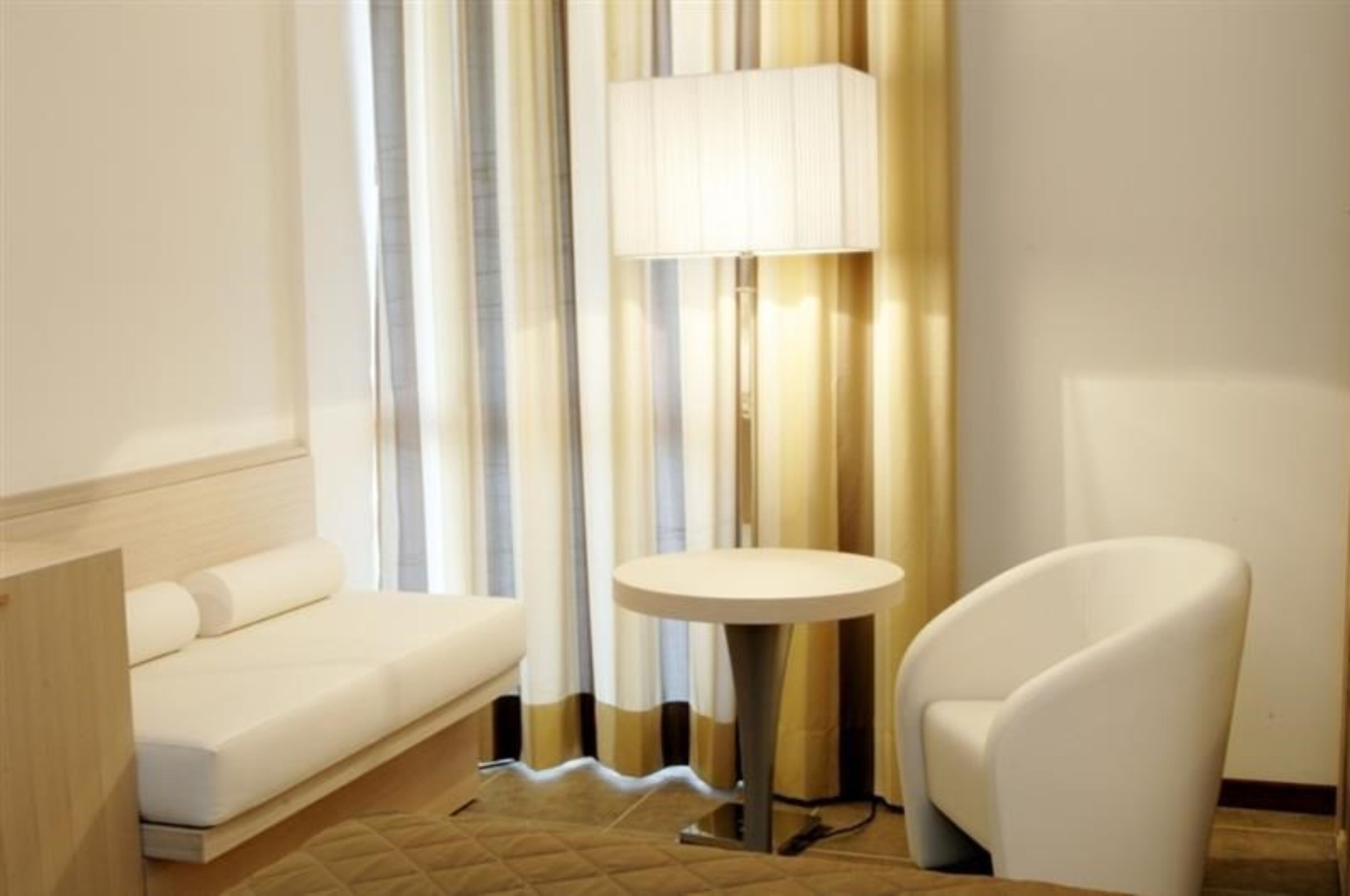 A modern hotel room with a white sofa, a round table, and a chair.