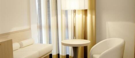 A modern hotel room with a white sofa, a round table, and a chair.