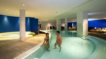 Een binnenzwembad, een buitenzwembad en parasols bij het zwembad