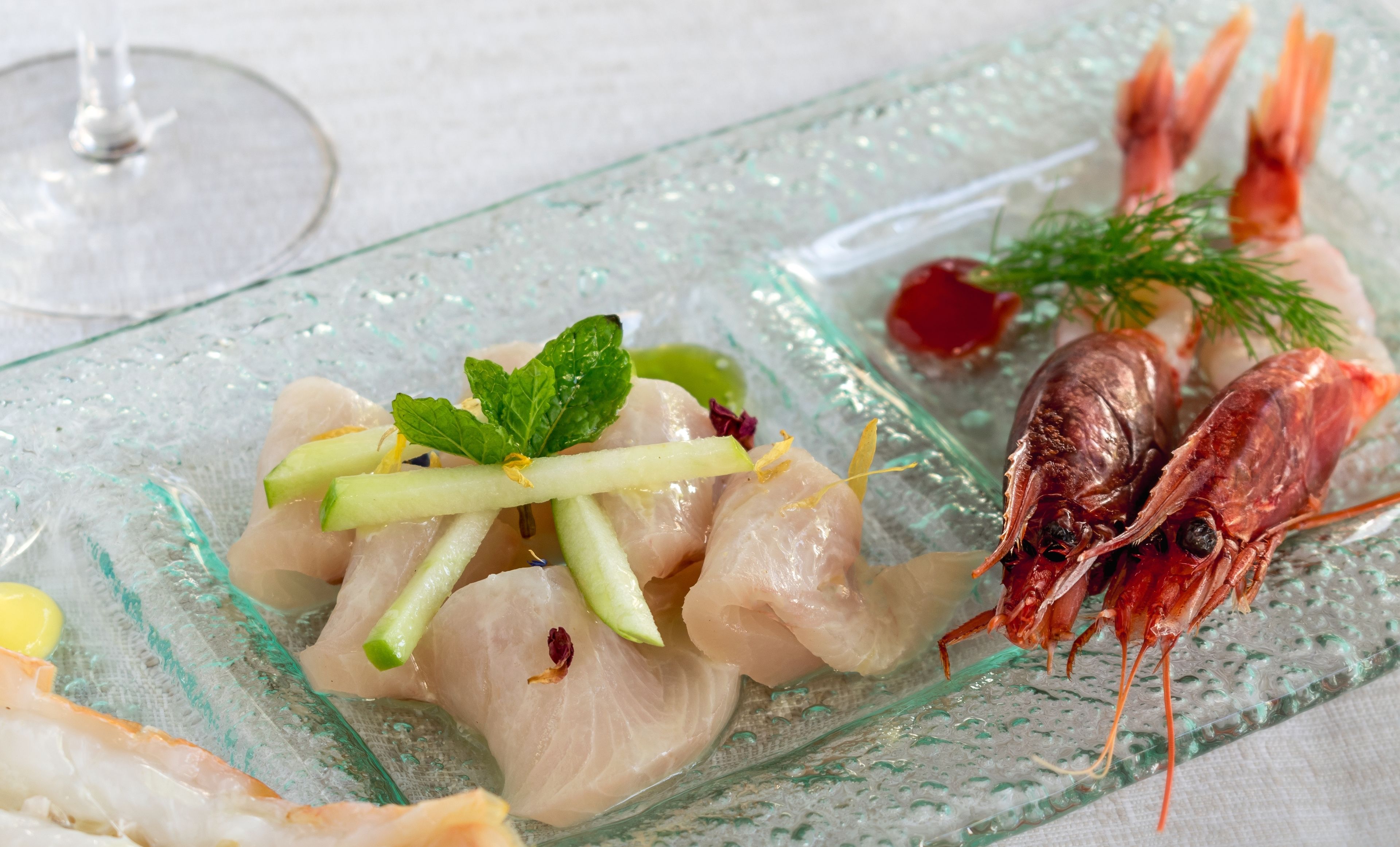 A seafood dish on a glass plate with shrimp and a garnish of herbs.