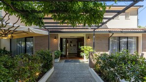 Una casa moderna con un porche cubierto, fachada de ladrillo y un camino de grava que lleva a la entrada.