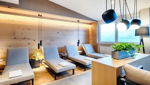 A modern spa room with wooden panel walls, multiple lounge chairs, a reception desk, and a potted plant. - Welcome Hotel Paderborn (Paderborn)