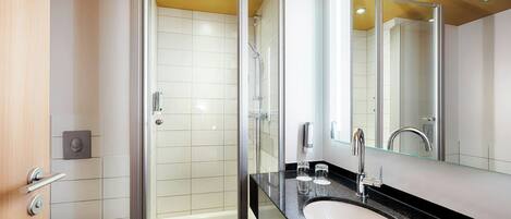 A modern bathroom with a glass-enclosed shower, a sink with a mirror, and a toilet.