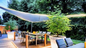 An outdoor patio area with a table and chairs, a potted plant, and a rope barrier. - Welcome Hotel Paderborn (Paderborn)