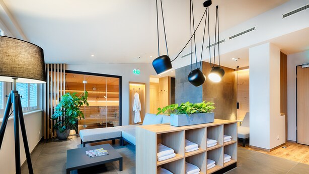 A modern hotel lobby with a reception desk, seating area, and a large potted plant. - Welcome Hotel Paderborn (Paderborn)