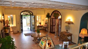 Un hall d’entrée spacieux, orné de colonnes décoratives, un grand escalier et une vue sur le jardin par les portes.