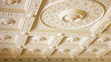 A ceiling with intricate floral and geometric patterns, likely part of a historic building's architecture.