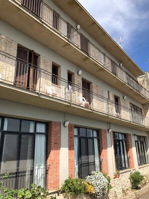 Un edificio de varios pisos con balcones, ventanas amplias y fachada de piedra.