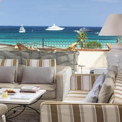 Relax in comfort with ocean views from this inviting outdoor seating area, featuring cushioned sofas and armchairs.