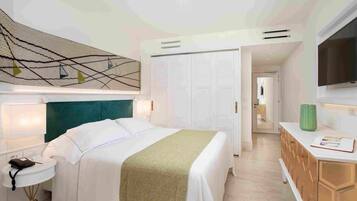 Ein Hotelzimmer mit Bett, Nachttisch, Lampe, Kleiderschrank und einem Fernseher an der Wand.