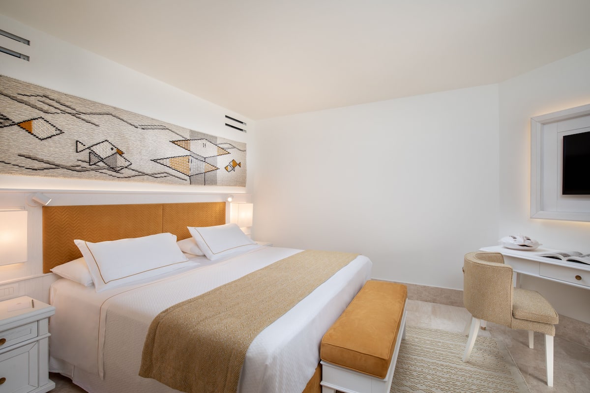 A modern hotel room with a large bed, a desk, and a television.