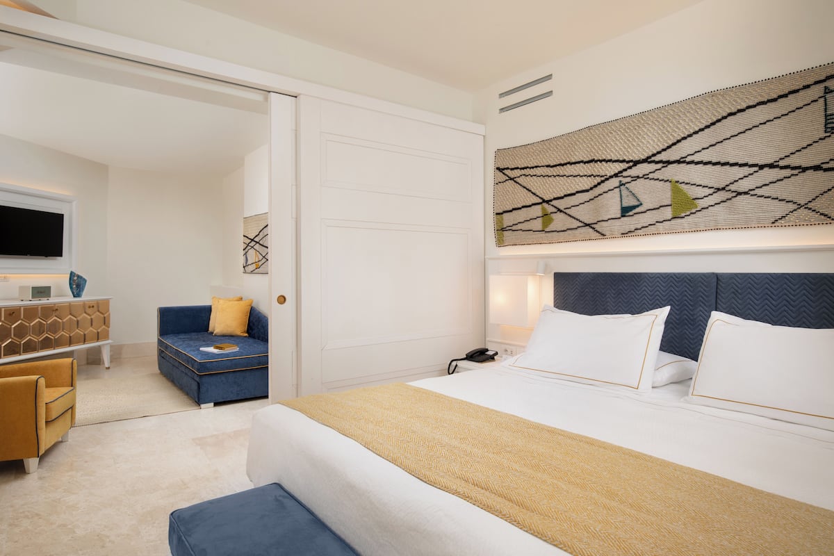 A hotel room with a bed, a sofa, a desk, and a television.