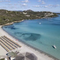 Relax on the beach with sun loungers and umbrellas, surrounded by lush greenery and calm waters.