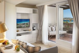 Un hotel moderno con balcón, televisión, comedor y vistas al mar.