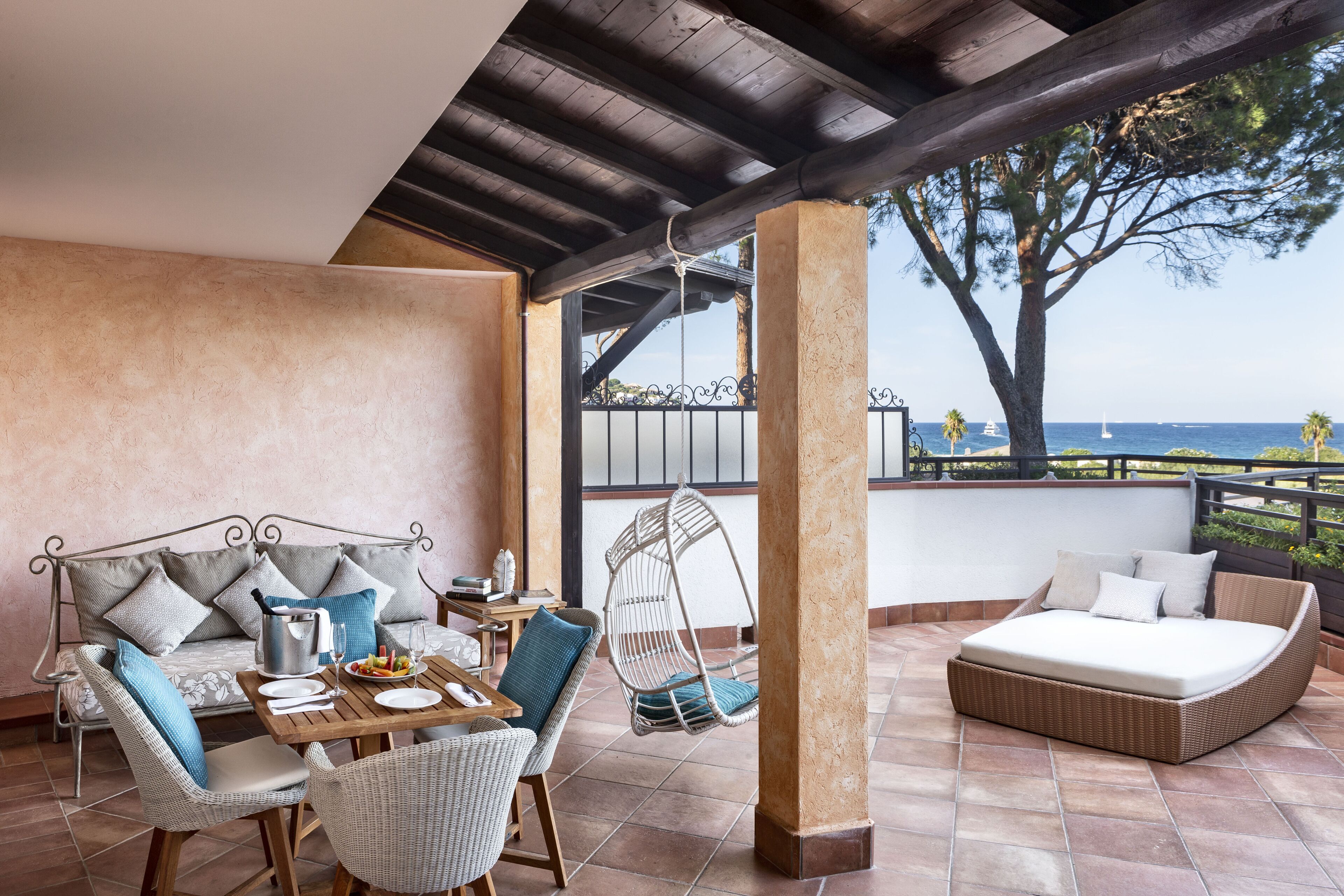 Une terrasse avec un canapé, une table à manger, des chaises et un fauteuil suspendu.