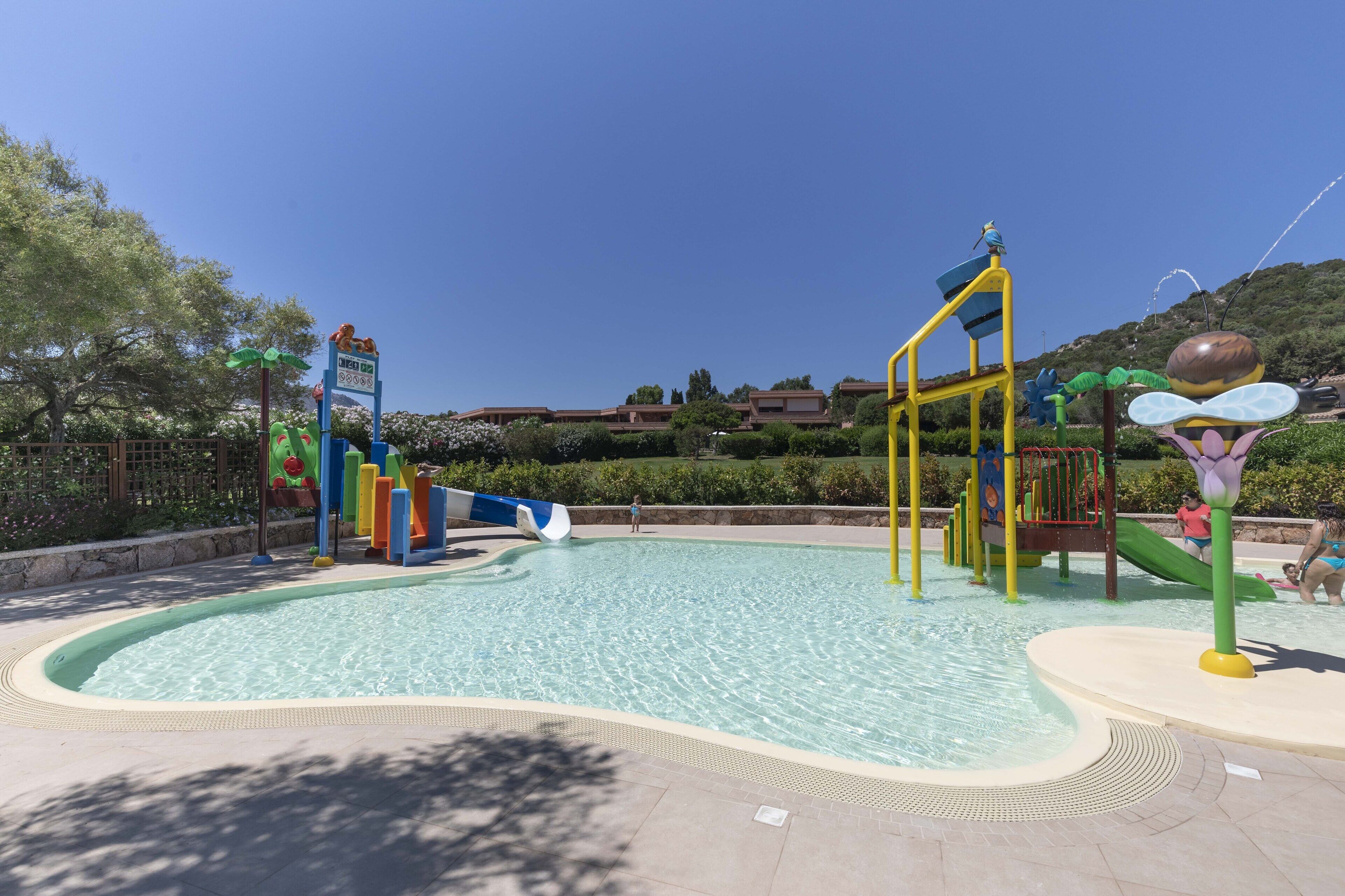A water park with a swimming pool, slides, and play structures.