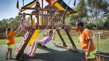 A playground with a wooden climbing structure and swings.