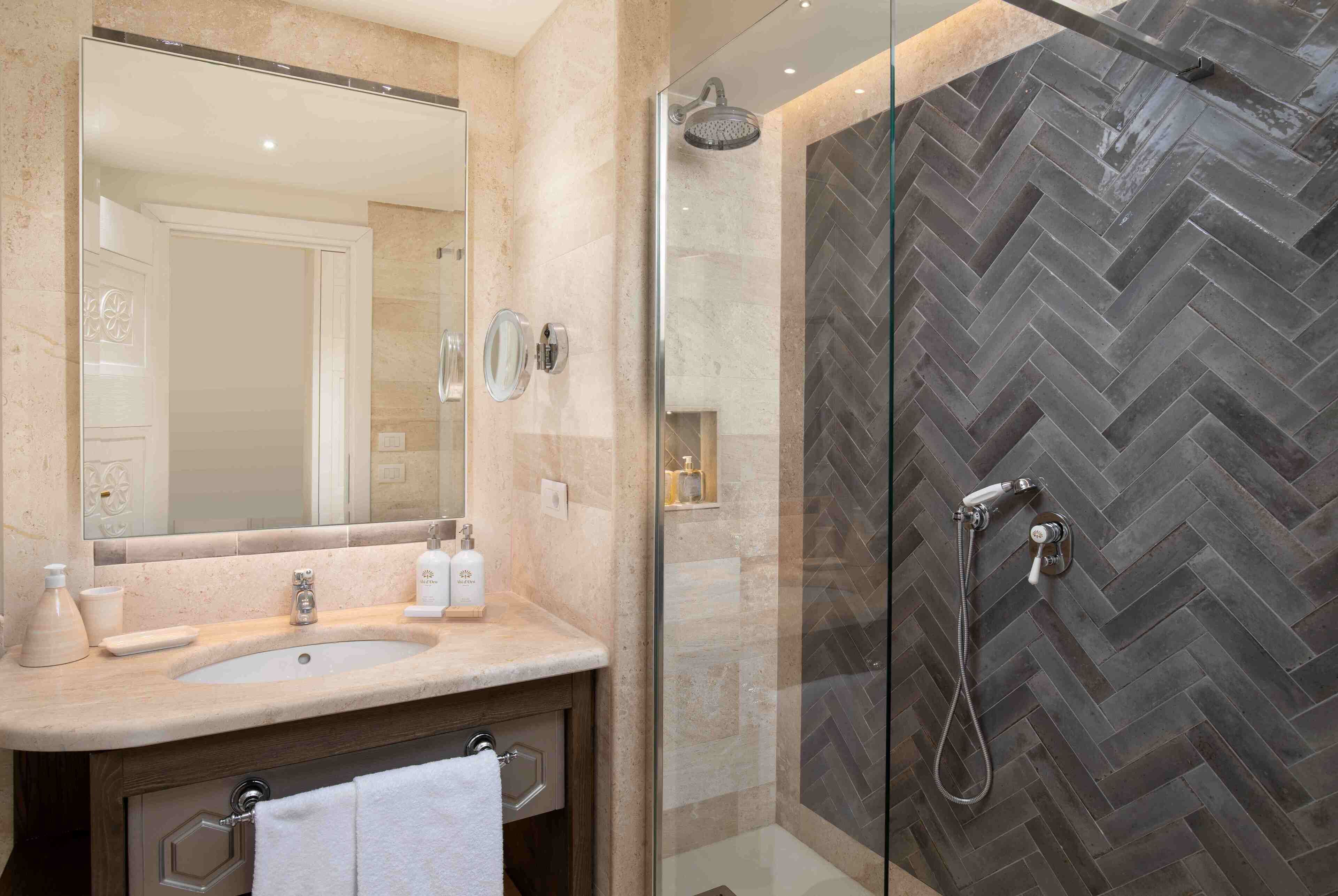 Un baño con un espejo grande, un lavabo y una zona de ducha con un patrón de baldosas en espiga.