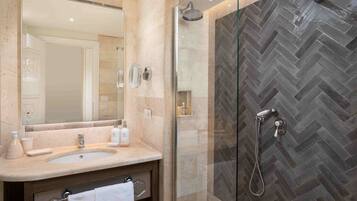 Un baño con un espejo grande, un lavabo y una zona de ducha con un patrón de baldosas en espiga.