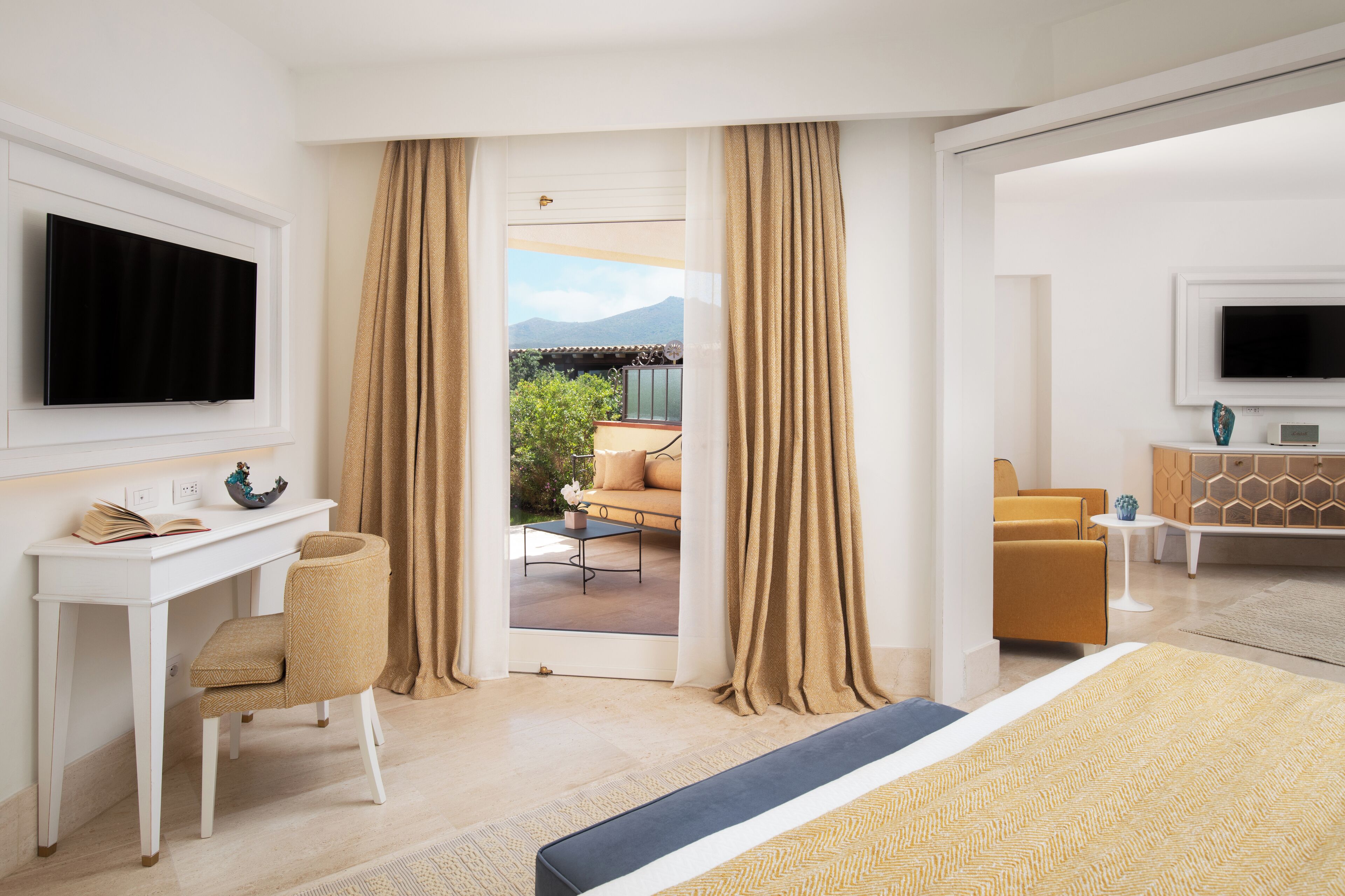 A hotel room with a bed, a desk with a chair, a TV, and a view of the outdoors.