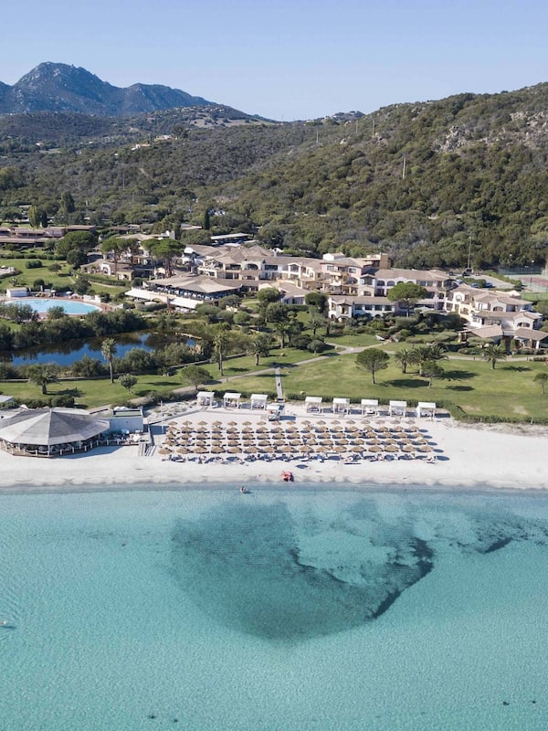 Relax on the beach with a villa, overlooking lush greenery and mountains.
