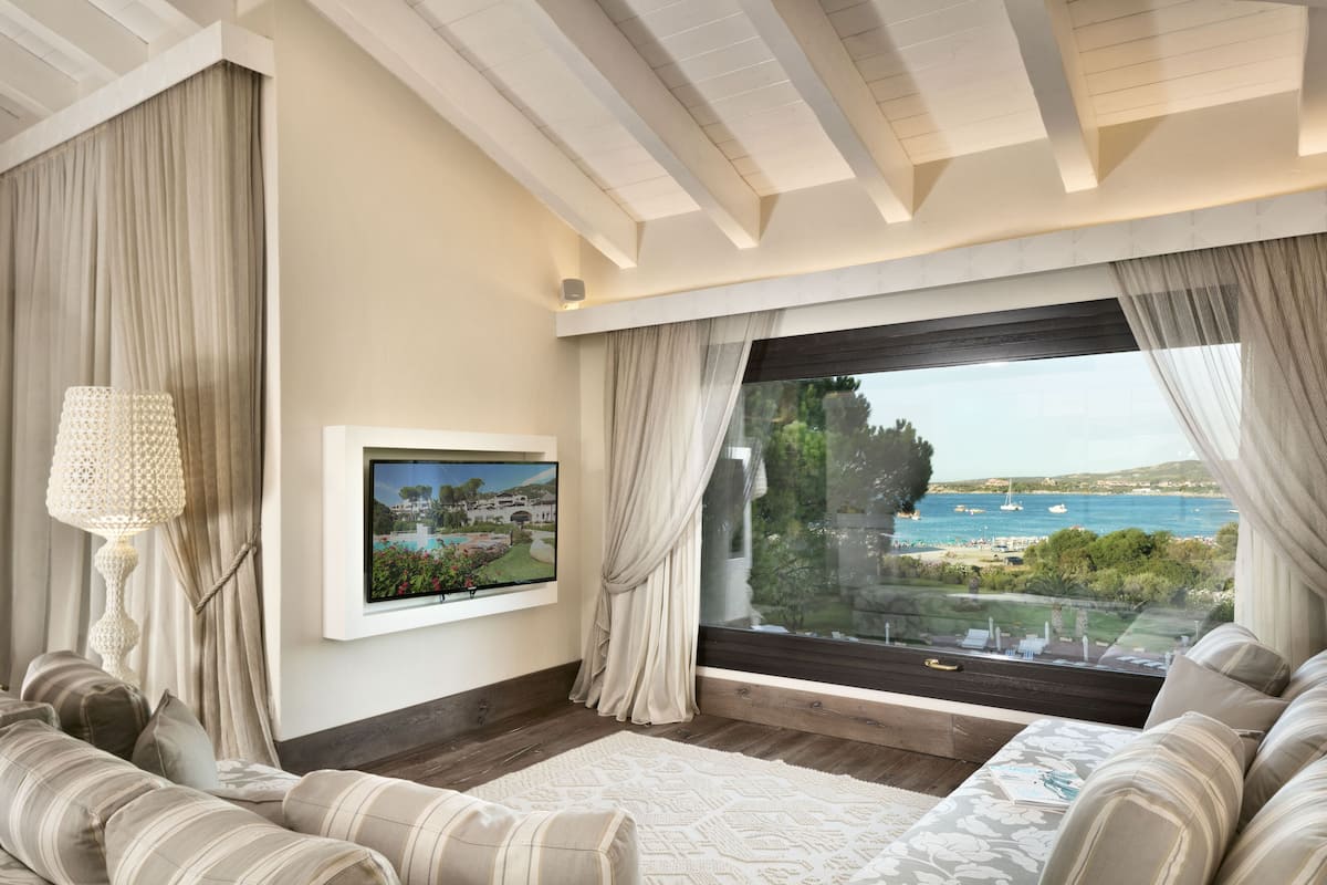A modern living room with a large window offering a scenic view of the sea and boats.