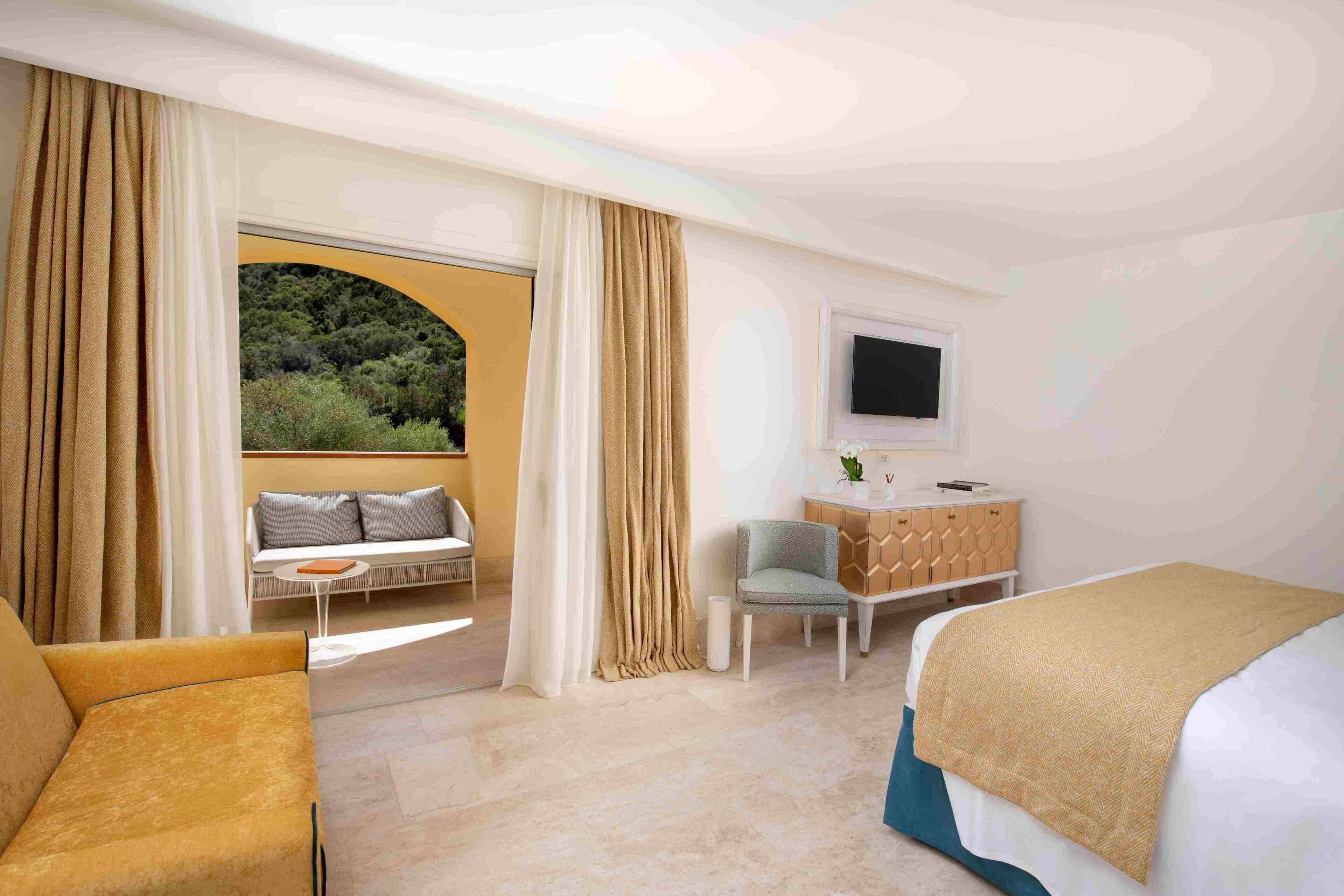 Een hotelkamer met een bed, een slaapbank, een fauteuil, een bureau en een televisie.