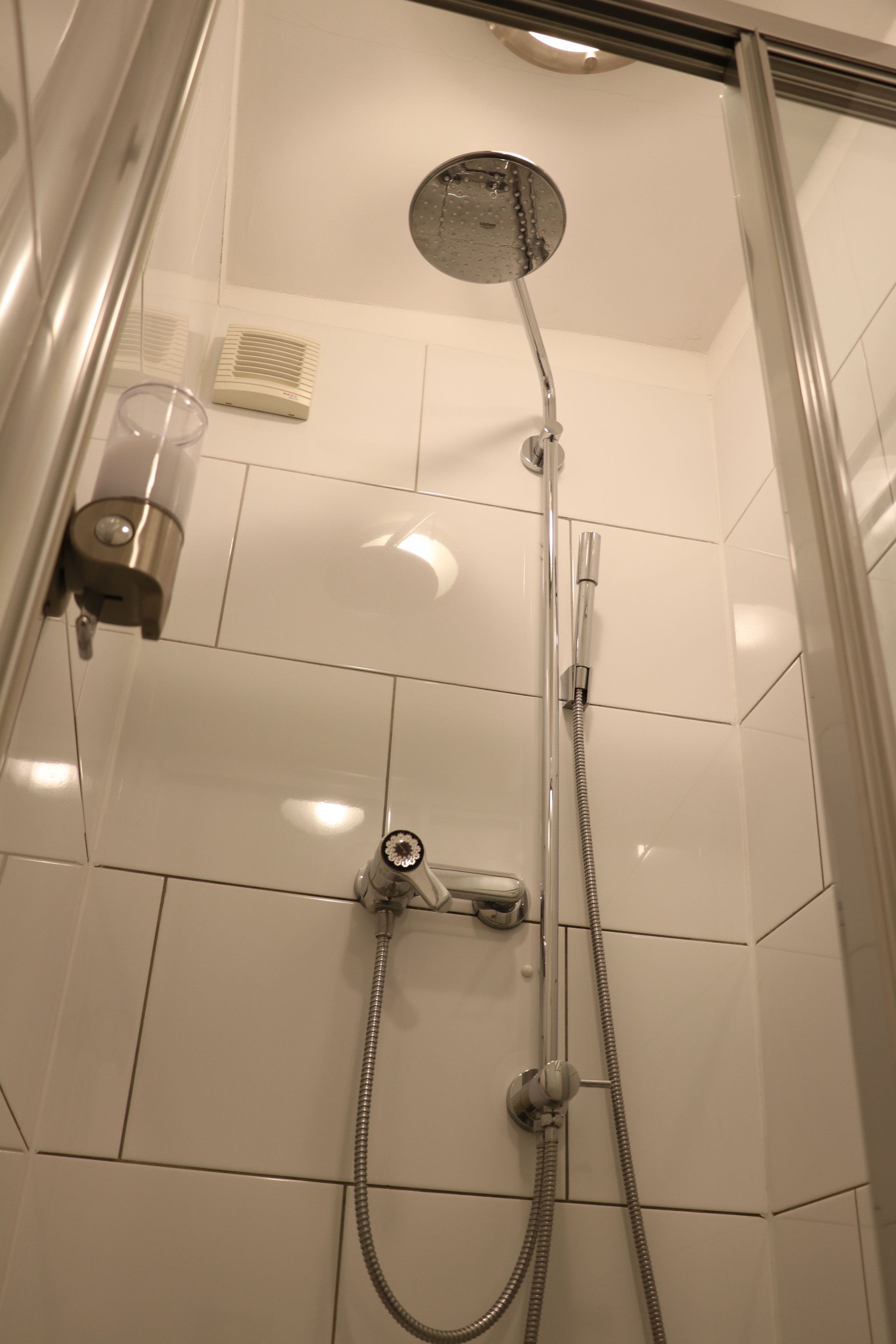 A shower with a handheld showerhead and a fixed showerhead, both with chrome finishes.
